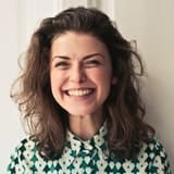 Smiling person with curly hair and patterned shirt.