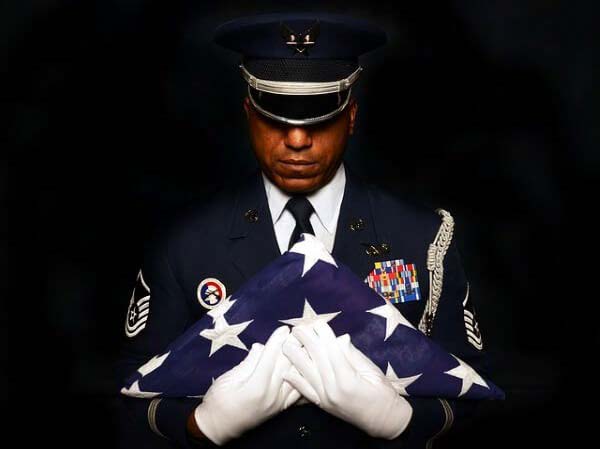 A soldier in uniform holding an american flag.