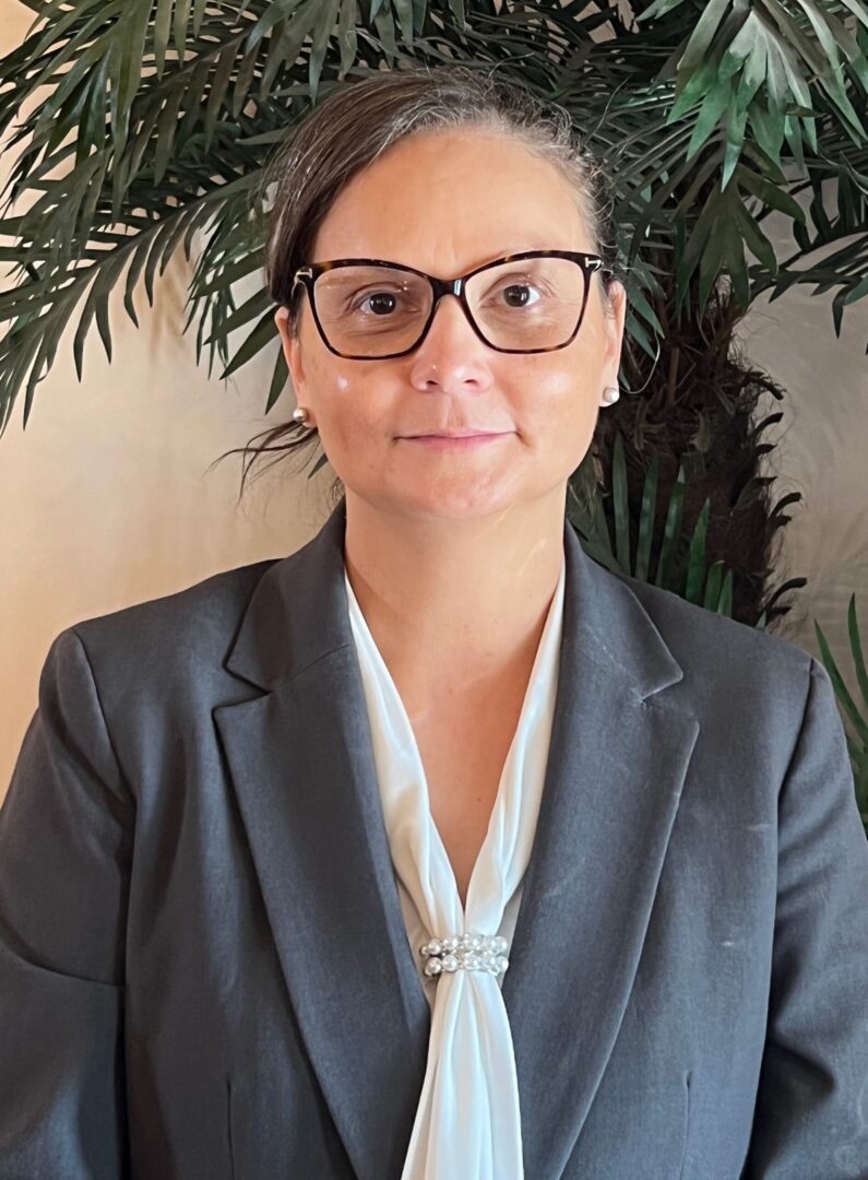 A woman wearing glasses and a suit.