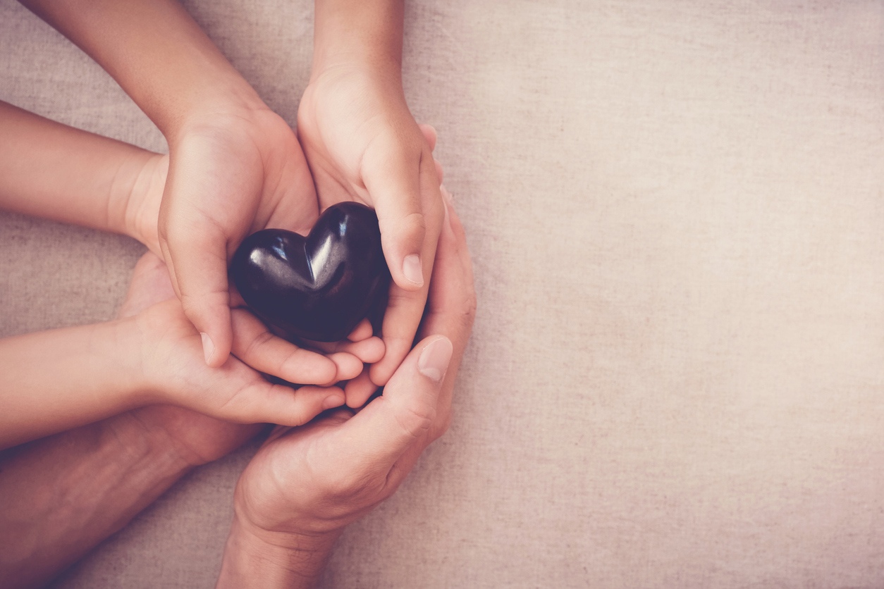 A group of people holding hands and a heart.