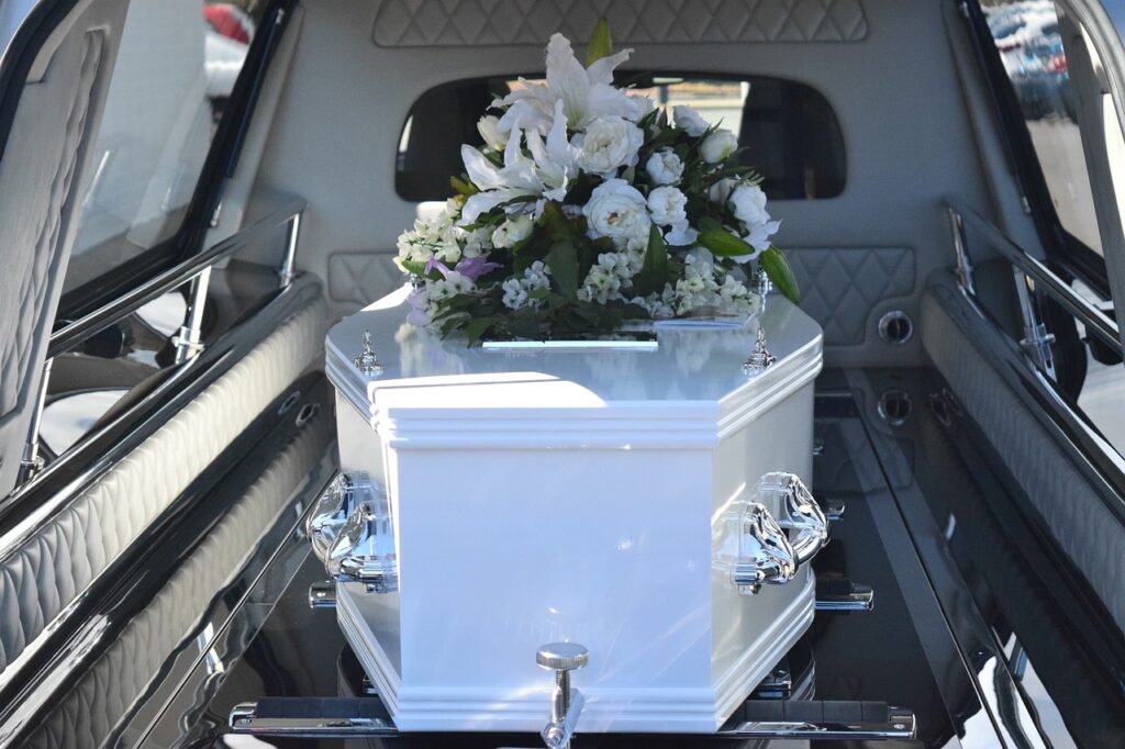 White casket with flowers in hearse.