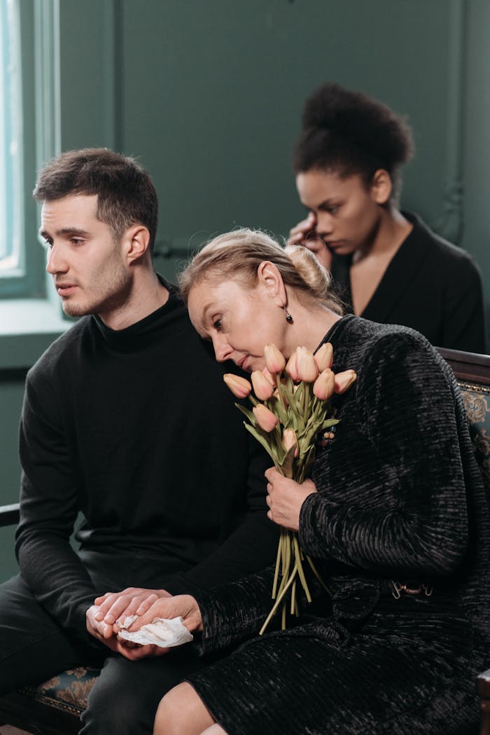 Mourning woman holding flowers with two men.