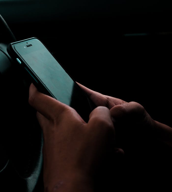 Hands using a smartphone in a car.